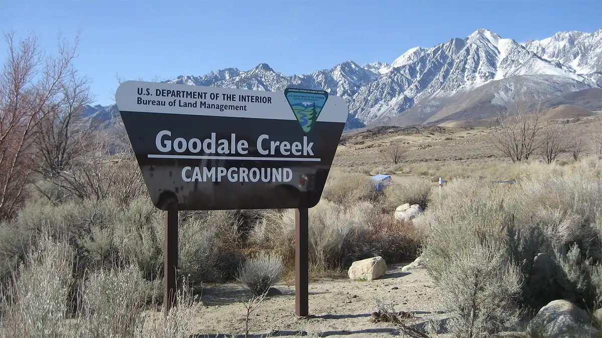 Photo of Goodale Creek Campground sign against snowy mountain peaks.